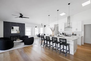 A modern kitchen with a central island, bar stools, and pendant lighting.