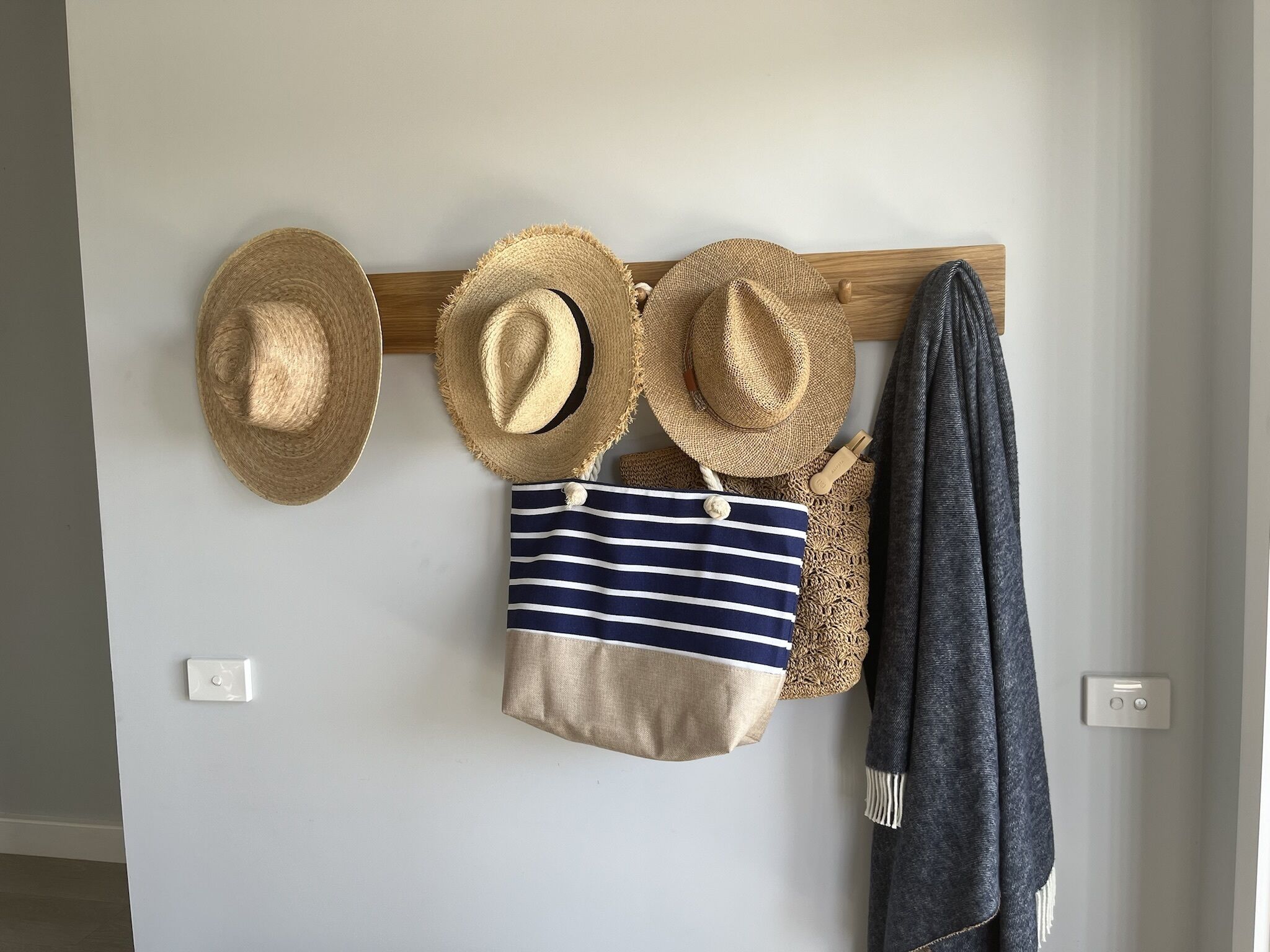 Una rastrelliera a parete con cappelli e una borsa a righe.
