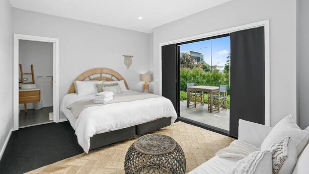 A modern bedroom with a large bed, a small table, and a view of the outdoors.