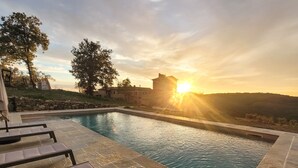 A swimming pool with lounge chairs, a stone wall, and a sunset in the background. - Exclusive Tuscan Winery Escape: Charming Villa with Pool & Breathtaking Views. (Radda in Chianti)