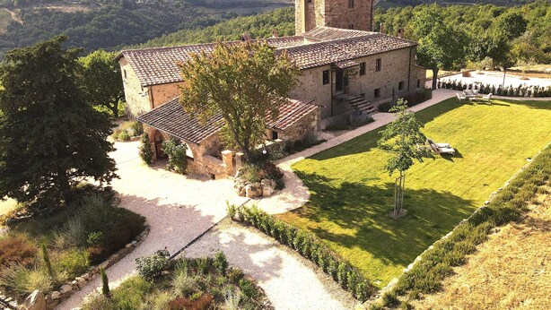 A stone building with a tiled roof, surrounded by a well-maintained lawn and a gravel path leading to the entrance. - Exclusive Tuscan Winery Escape: Charming Villa with Pool & Breathtaking Views. (Radda in Chianti)