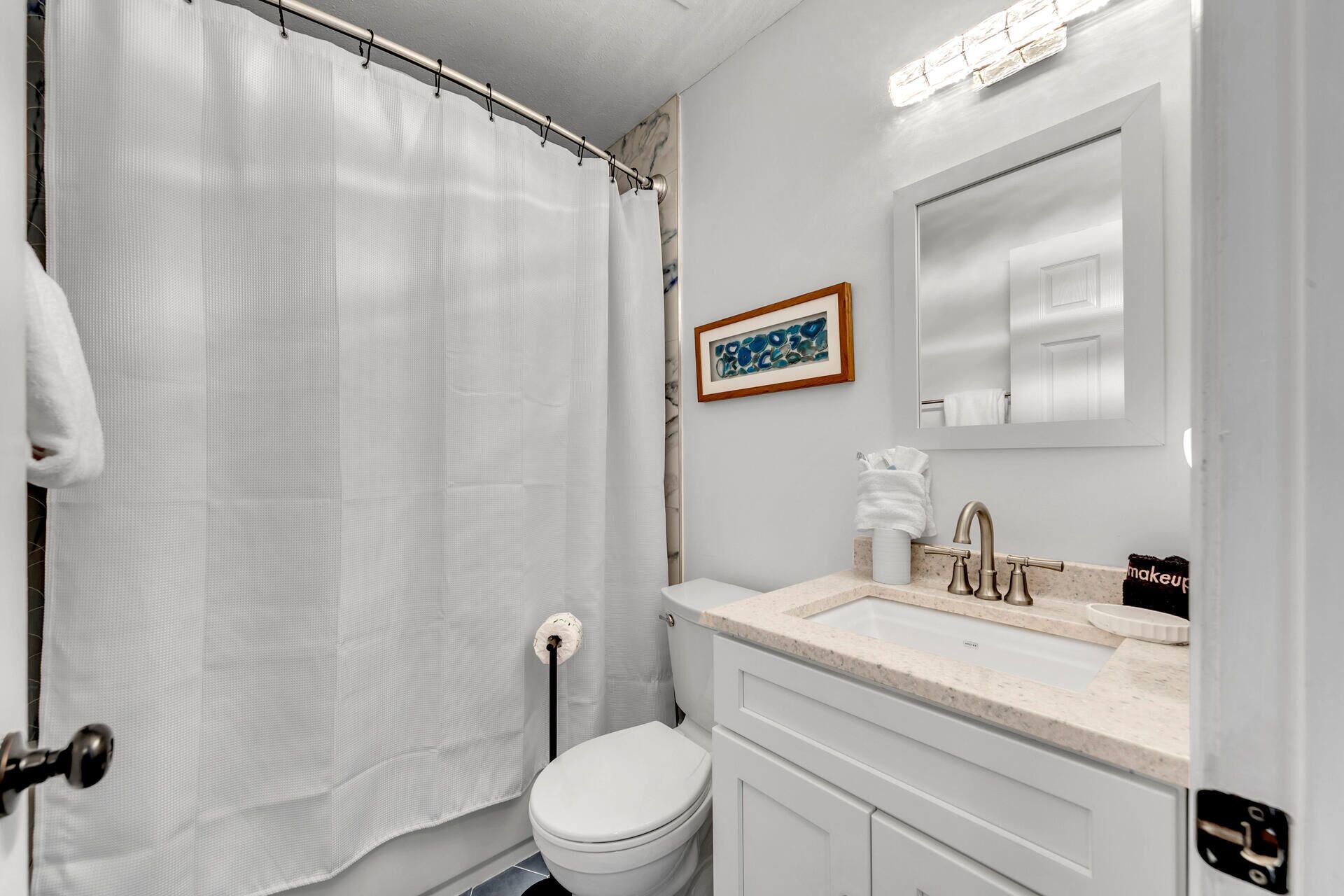 A bathroom with a toilet, sink, and shower curtain.