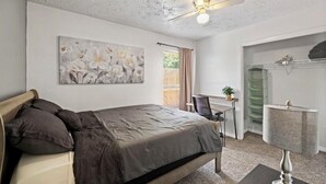 A bedroom with a bed, a ceiling fan, a desk with a chair, a lamp, and a wardrobe. - Cozy 2 Bed 1 Bath Home near IAH (Spring)