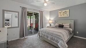 A bedroom with a bed, a ceiling fan, a sliding glass door, a chair, and a lamp. - Cozy 2 Bed 1 Bath Home near IAH (Spring)