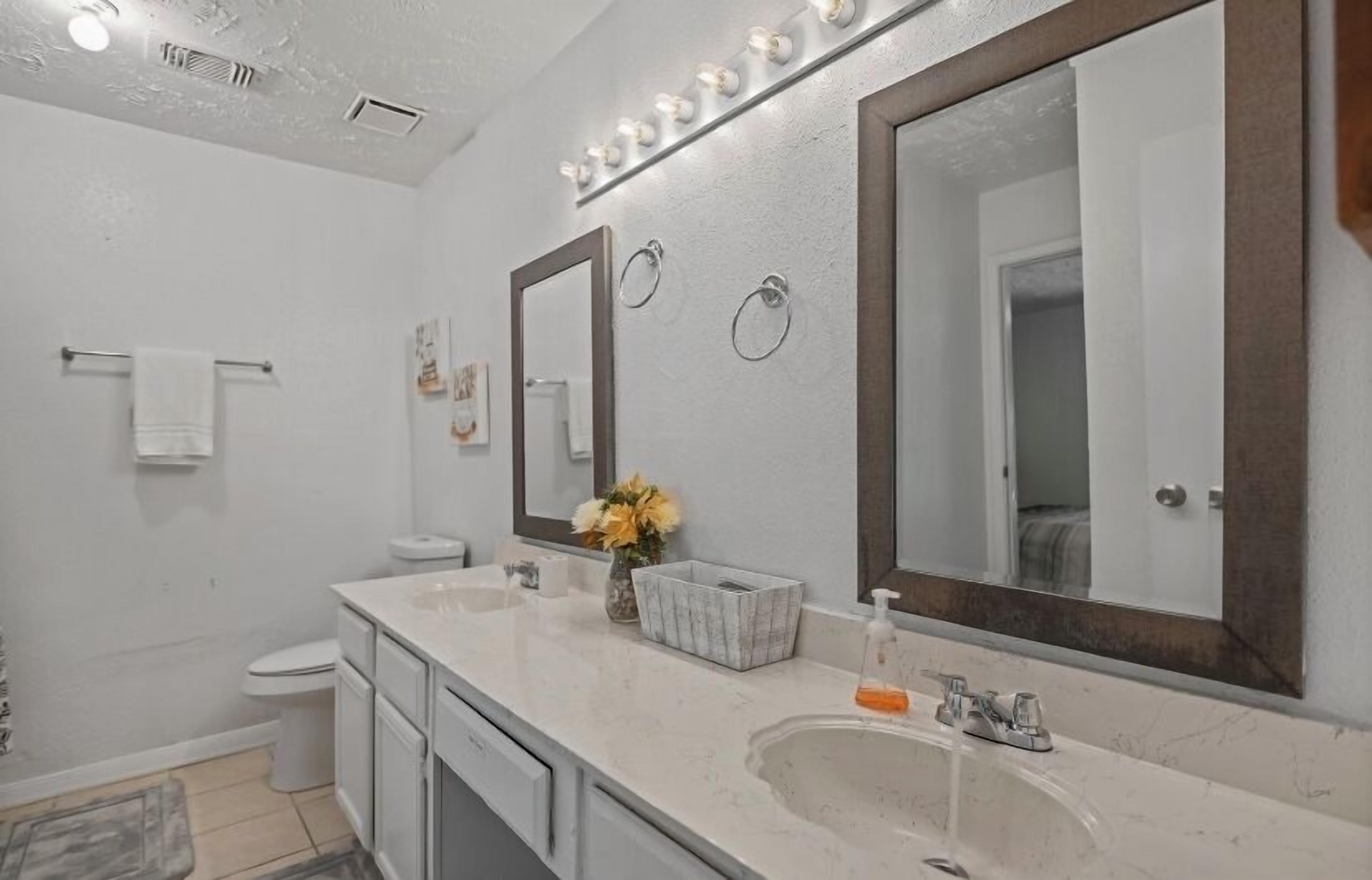 A modern bathroom with two sinks, a large mirror, and a vanity.