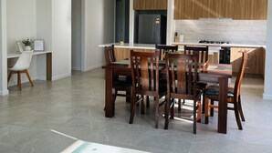 Eine moderne Küche mit Holzausbau, einem eingebauten Herd und einem Essbereich mit einem Glastisch und Holzstühlen.