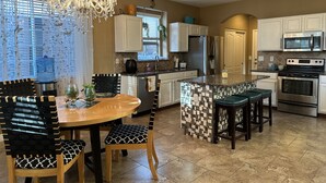 Una cocina moderna con una isla central, electrodomésticos de acero inoxidable y una araña.