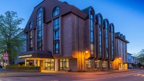 Un hotel moderno con fachada de ladrillo, ventanas grandes y un letrero que dice 'Hotel Stadt Gutersloh'.