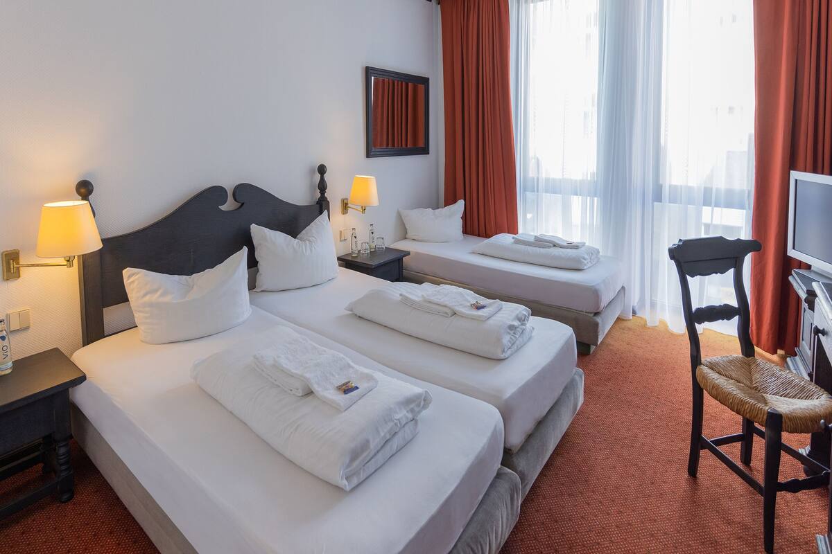 Habitación de hotel con dos camas, televisión, escritorio y una silla.