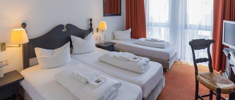 A hotel room with two beds, a TV, a desk, and a chair.