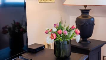 Un téléviseur posé sur une table en bois, avec un vase de fleurs et une lampe.