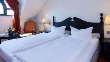 A hotel room with a large bed, two bedside tables, a chair, and a window with curtains.