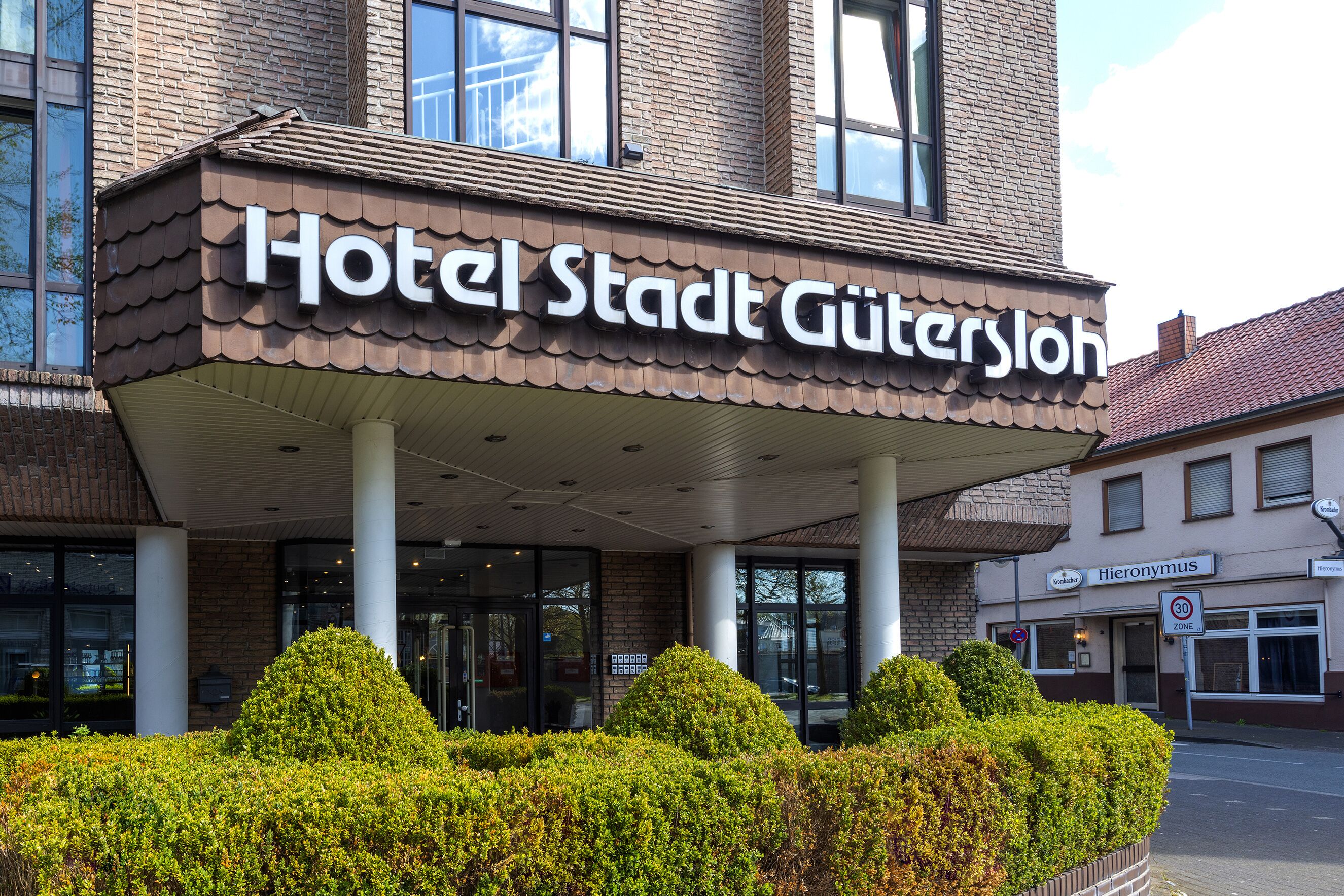 A hotel entrance with a sign reading "Hotel Stadt Gutersloh".