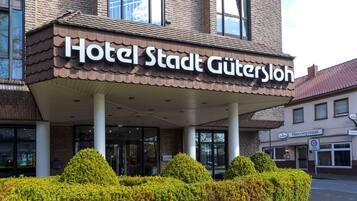 A hotel entrance with a sign reading "Hotel Stadt Gutersloh".