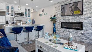 A modern kitchen with a bar area, a dining table with chairs, a fireplace, and decorative wall art. - Sunset Paradise - Find yourself in Tampa (Tampa)