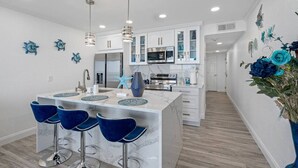 A modern kitchen with white cabinets, a central island with bar stools, and decorative wall art. - Sunset Paradise - Find yourself in Tampa (Tampa)