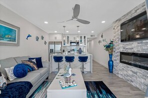 A modern living room with a sofa, coffee table, and a kitchen area with bar stools.