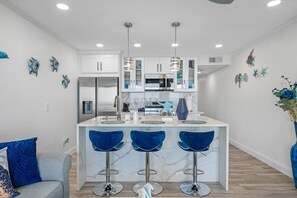 A modern kitchen with a central island, bar stools, and decorative wall art.
