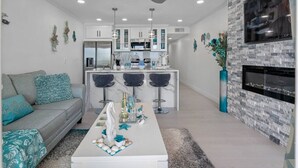 A modern living room with a sofa, coffee table, and kitchen area with bar stools.