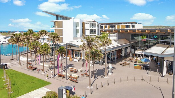 Un hôtel moderne offrant une vue sur le port de plaisance, doté d’une terrasse et agrémenté de palmiers.