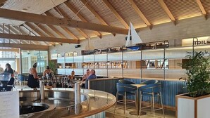 Un espace bar moderne doté d’un comptoir incurvé, de plusieurs options d’aménagement pour s’asseoir et d’un haut plafond en bois avec des lambris.
