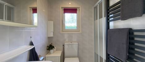 A bathroom with a white sink, toilet, and a window with a view of greenery.
