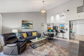 A modern living room with a leather sofa, a coffee table, and a dining area with a round table and chairs.