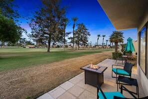 A patio with a fire pit, outdoor furniture, and a view of a golf course.