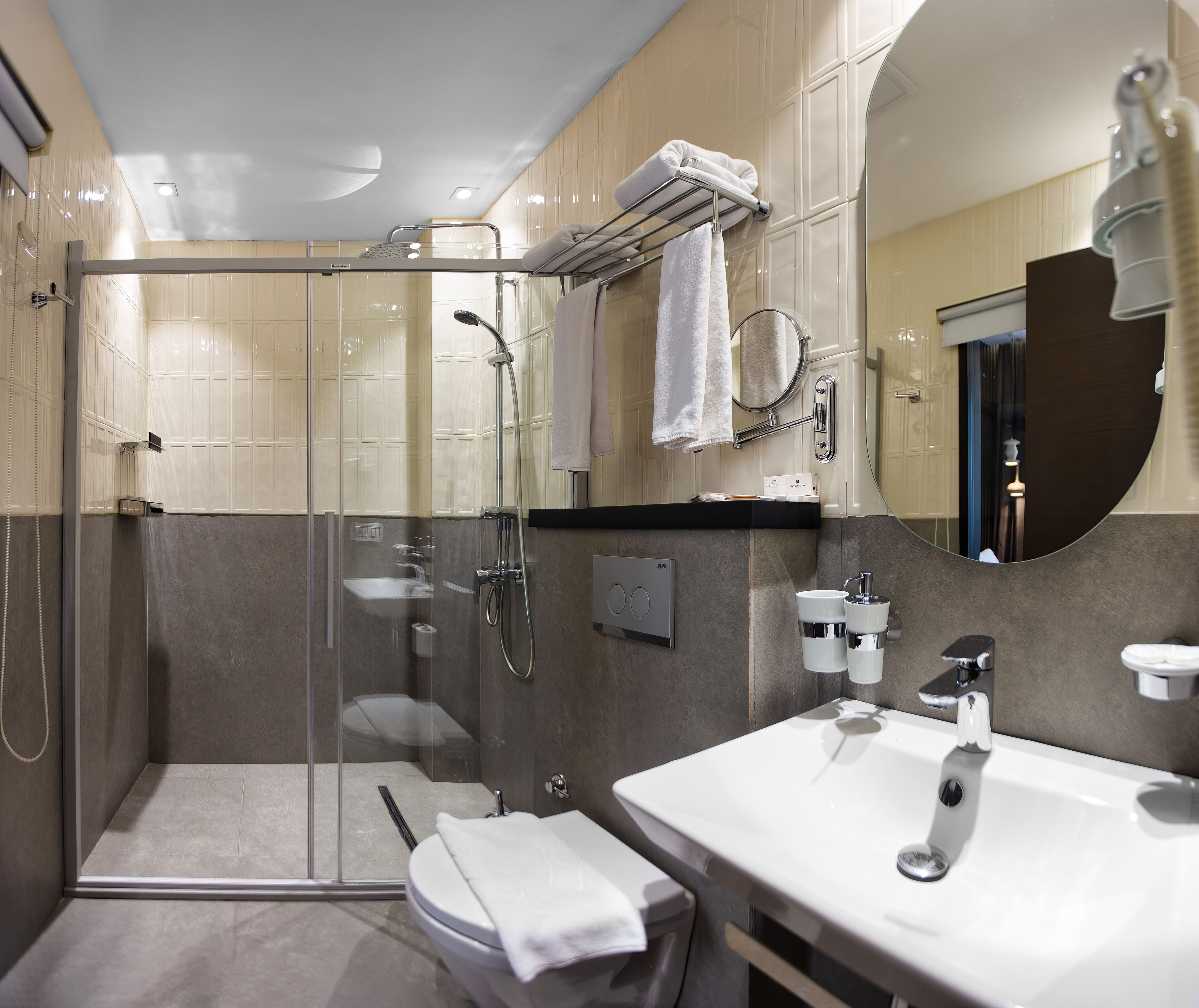 Une salle de bain moderne avec une douche à parois de verre, un lavabo blanc et un grand miroir.