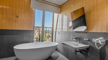 A modern bathroom with a freestanding bathtub, a wall-mounted sink, and a large mirror.