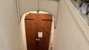 A narrow stairway leading to a wooden door with a sign above it.