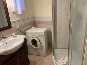 A bathroom with a washing machine, a sink, and a glass-enclosed shower. - Purgatorio Double in Firenze (Florence)