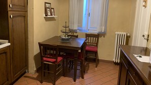A small, cozy kitchen with a dining table, chairs, and a window with curtains.