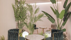A room with a round table and two chairs, surrounded by various plants and a small side table. - Denbasta heritage Hotel (Gyeongju)