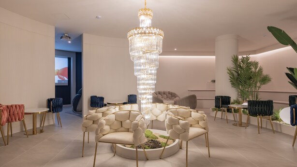 A modern interior with a central chandelier, round seating, and a projector screen in the background. - Denbasta heritage Hotel (Gyeongju)