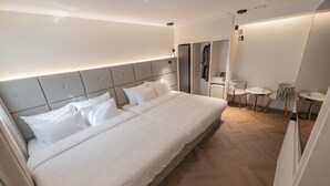 A modern hotel room with a large bed, a small seating area with two chairs and a table, and a mirror on the wall. - Denbasta heritage Hotel (Gyeongju)