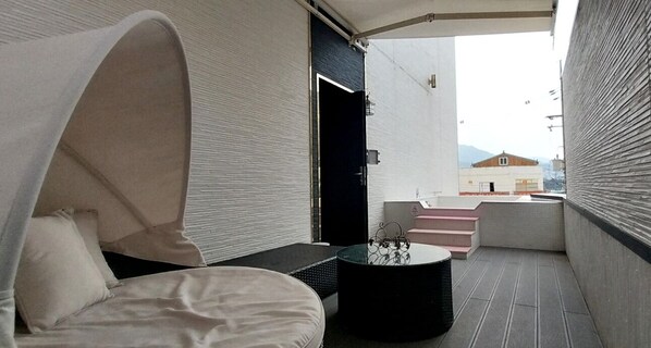 A modern bedroom with a bed, a small table, and a view of a building through an open door. - Denbasta heritage Hotel (Gyeongju)