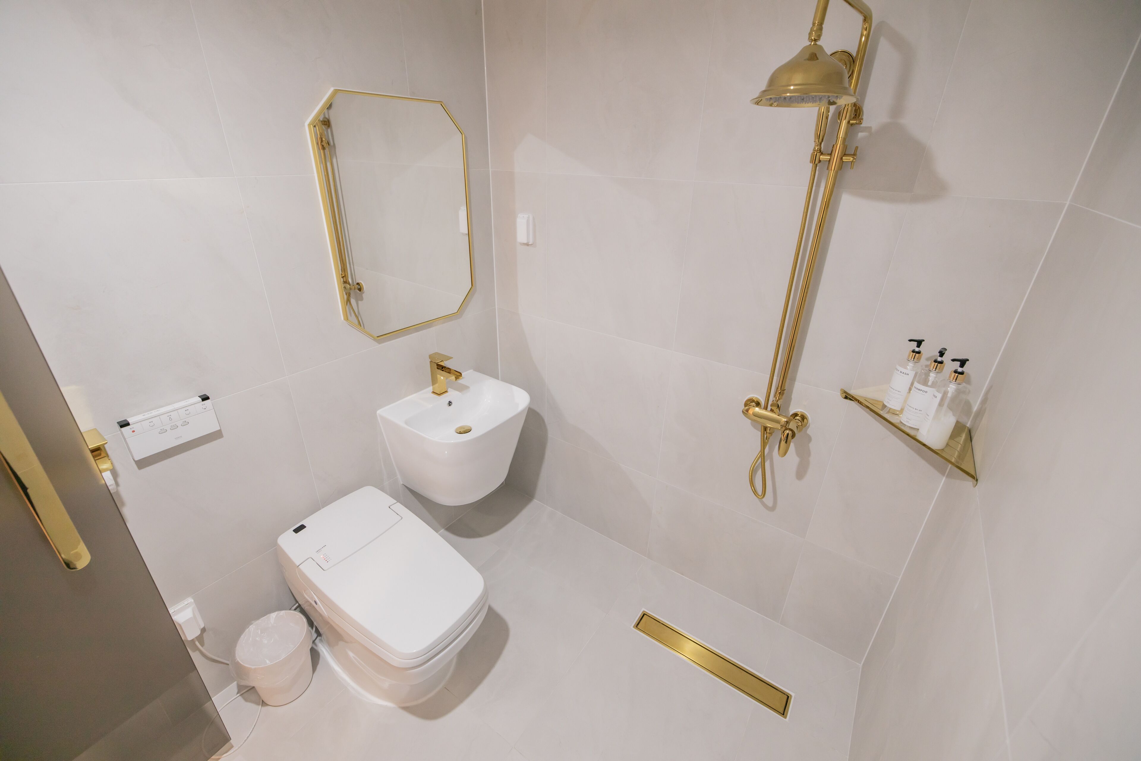 Un baño moderno con inodoro, bidé y detalles dorados.