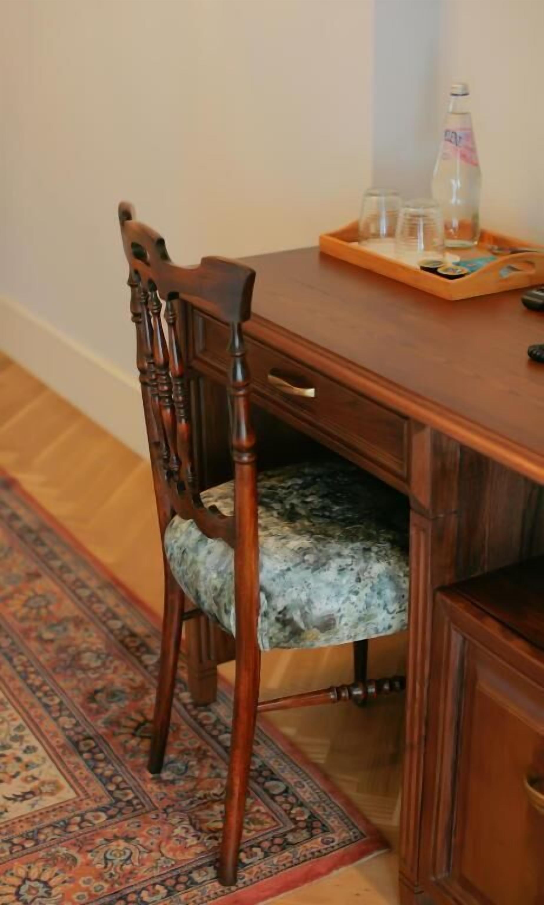 A wooden dining table with a tray holding glasses and a bottle.