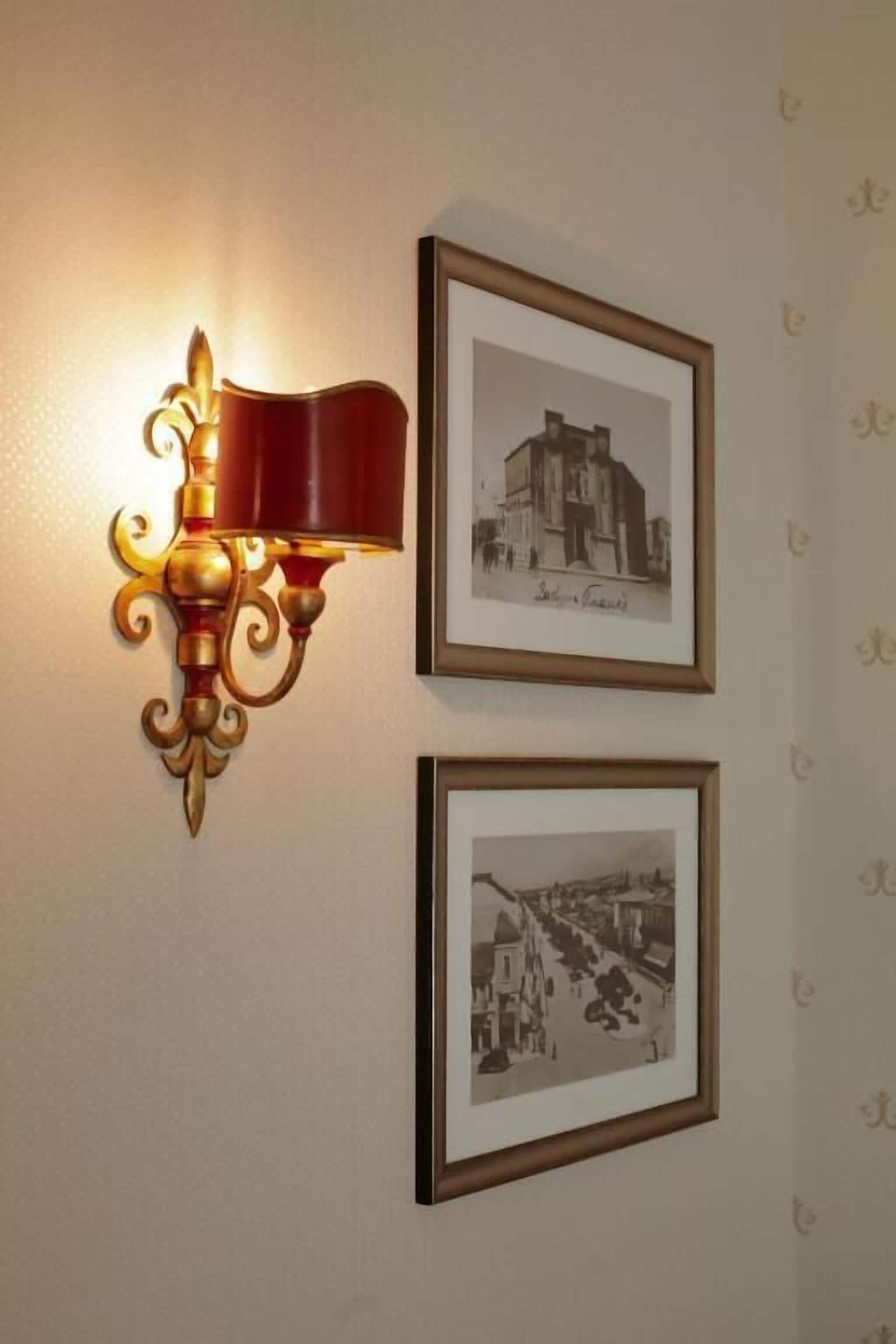 Una lámpara de pared con un diseño decorativo y dos fotografías en blanco y negro enmarcadas.
