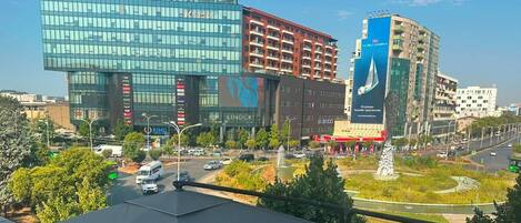 A modern building with a glass facade, a parking lot, and a fountain in the foreground.