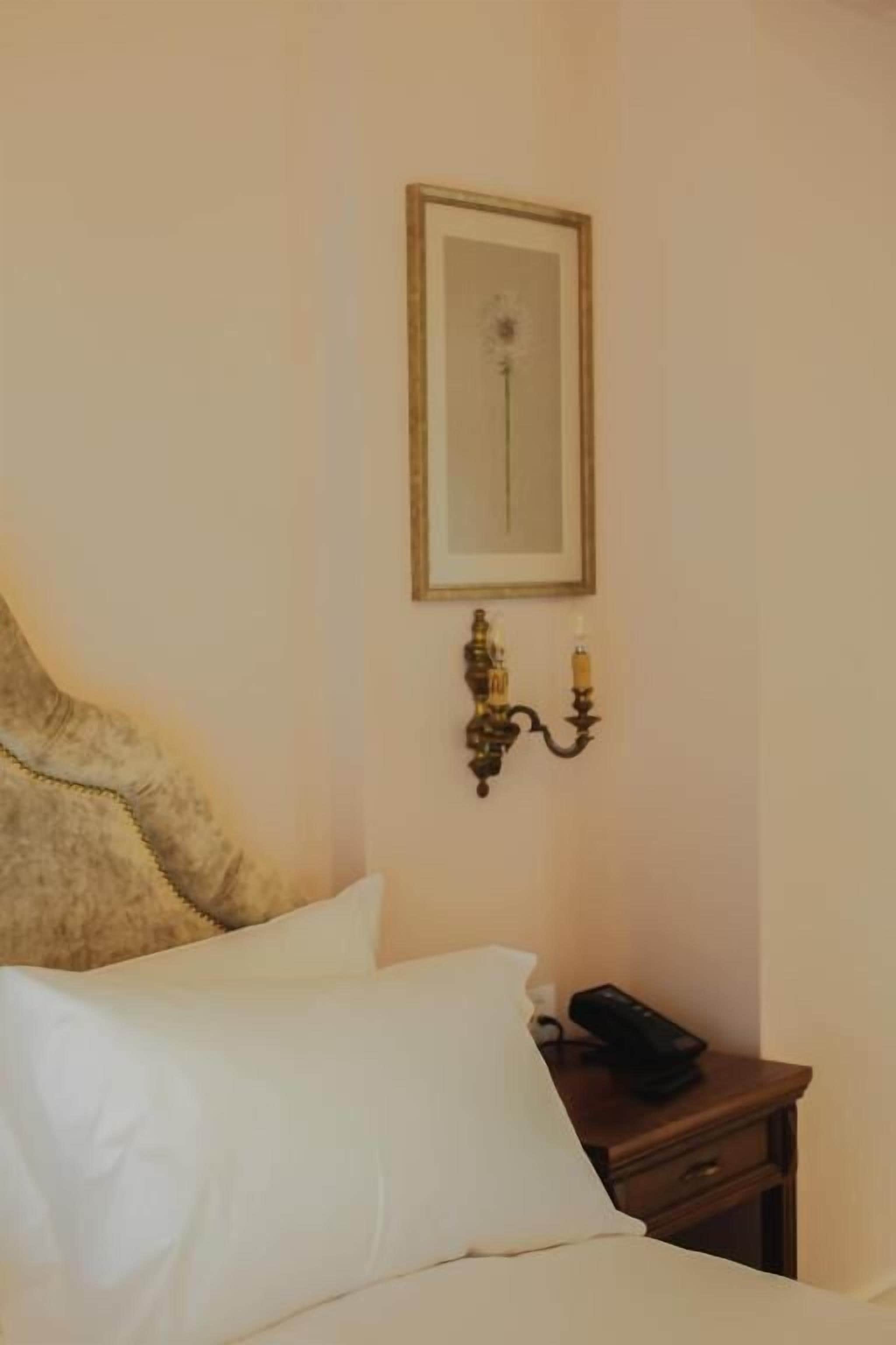Une chambre d’hôtel avec un lit, une table de chevet avec une lampe et un tableau encadré au mur.