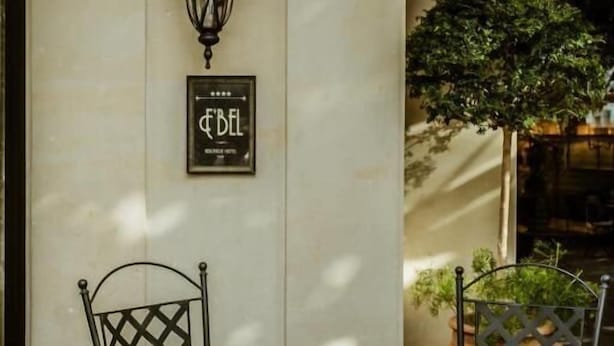 Un espace extérieur aménagé avec une table et des chaises, une plante en pot et un panneau fixé au mur.