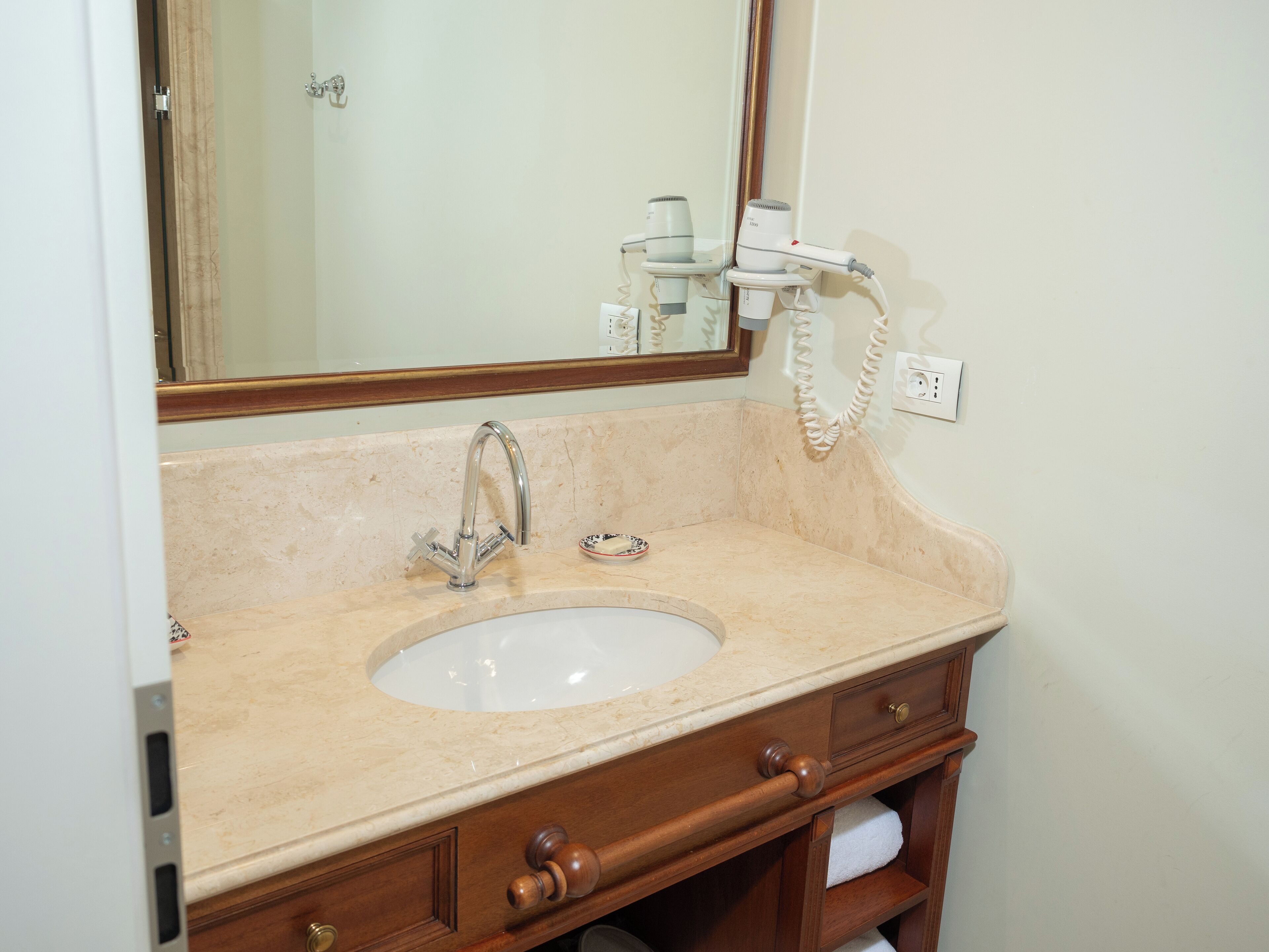 A bathroom with a sink, mirror, and towel rack.