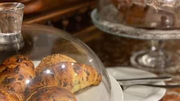 Une table en marbre surmontée d’un présentoir en verre où sont exposés des croissants et un gâteau.