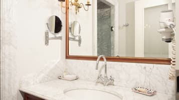 A bathroom with a marble sink, two mirrors, a chandelier, and a hairdryer.