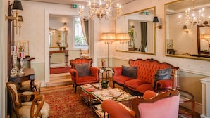Une chambre luxueuse avec un canapé rouge, des lustres richement décorés et de grands miroirs.