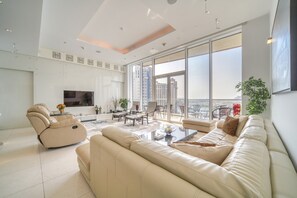 Ein geräumiges Wohnzimmer mit einer großen Couch, einem Relaxsessel und einem Essbereich mit einem Glastisch.