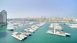 Un port de plaisance où sont amarrés de nombreux bateaux, un grand bâtiment sur la gauche et une vue sur la ville en arrière-plan.