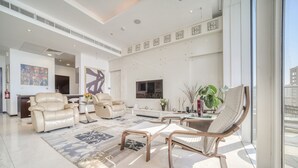 Un vaste espace de vie agrémenté de canapés en cuir, d’un grand tapis et d’un téléviseur moderne.